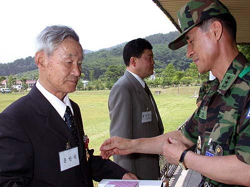 53사단장이 문인식옹에게 훈장를 달아 주고 있다. 